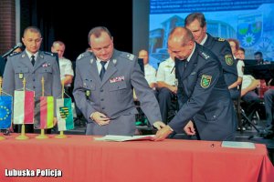 Generał Policji siada żeby podpisać dokumenty