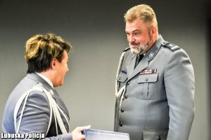Komendant Wojewódzki Policji przekazuje prezent policjantowi.