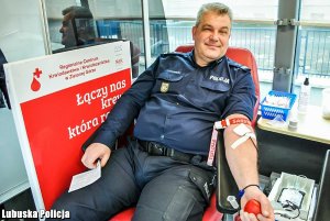 Policjant oddaje krew przy krwiobusie.