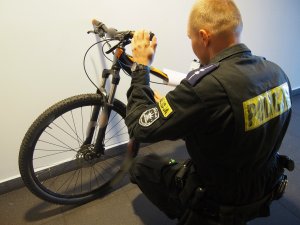 Policjant przy rowerze górskim w pomieszczeniu.