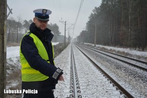 Policjant drogówki na tle torów kolejowych.