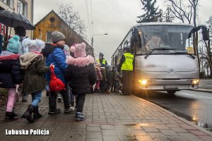 Dzieci wchodzące do autobusu, przy którym stoją policjantki.