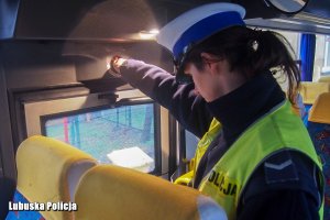 Policjantka drogówki kontroluje stan techniczny autobusu.