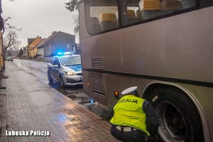 Policjantka kontroluje ogumienie autobusu.