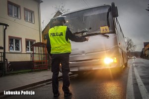 Policjantka kontroluje oświetlenie autobusu.