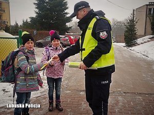 Policjant wręczający odblaski dzieciom.