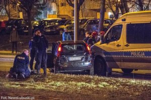 Policjanci i zatrzymani leżący na ziemi oraz rozbity samochód po pościgu