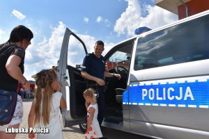 dzieci rozmawiają z policjantem przy radiowozie