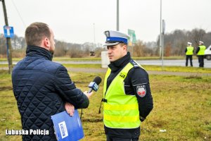 Policjant ruchu drogowego w kamizelce odblaskowej udzielający wywiadu dziennikarzowi