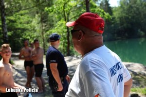 Instruktor wodny i policjanci przy jeziorze wraz z kąpiącymi się