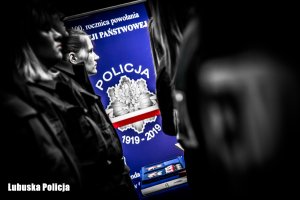 policjanci i baner na 100. rocznice powołania Policji Państwowej