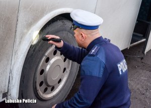 Policjant sprawdza stan techniczny autokar.