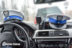 Policyjne czapki policjantów ruchu drogowego na kokpicie radiowozu