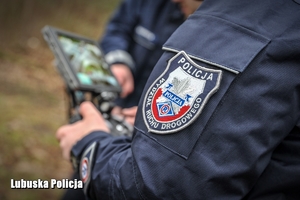 Policyjna naszywka na mundurze policjanta, który steruje dronem powietrznym.