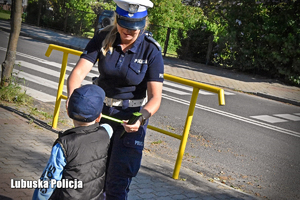 Policjantka rozdaje odblaski dzieciom