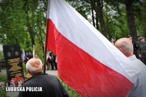 Mężczyzna trzymający biało - czerwoną flagę.