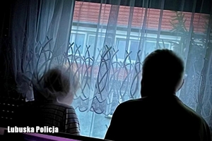 Dwie starsze osoby wyglądają przez okno mieszkania