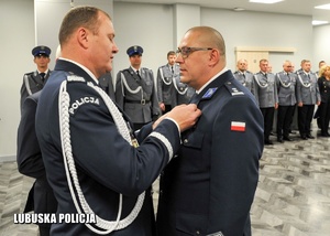 Komendant Wojewódzki Policji przypina medal policjantowi.