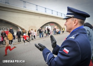 Policjant oklaskujący uczestników biegu ulicznego.