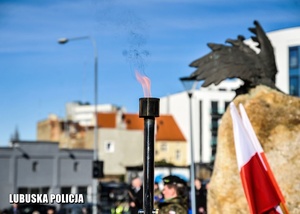 Płomień przy fladze Polski podczas uroczystości.