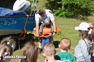 policyjny wodniak rozmawia z dziećmi i uczy je zasad bezpieczeństwa nad wodą