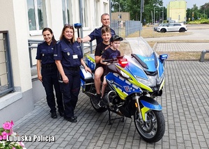Policjanci stojący przy motocyklu policyjnym w otoczeniu dwóch chłopców.