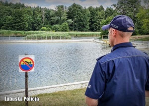 Policjant stojący przed zbiornikiem wodnym.