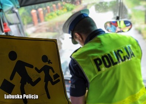 Znak dotyczący przewozu dzieci, a w tle policjant drogówki.