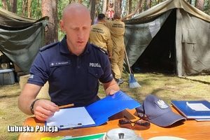 policjant sprawdza dokumentację w obozie