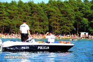 Policjanci obserwują kąpiących się w jeziorze.
