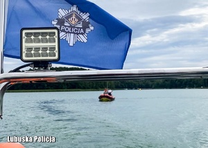 Flaga z napisem Policja na motorówce płynące po jeziorze.