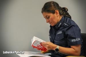 Policjantka z korzysta z kodeksu podczas rozwiązywania testu.