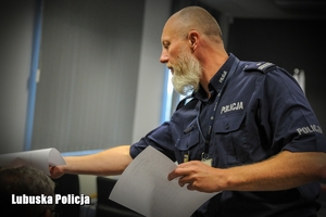 Policjant rozdaje testy uczestnikom konkursu.