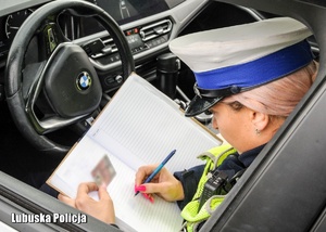 Policjantka drogówki podczas dokumentowania czynności w notatniku służbowym.