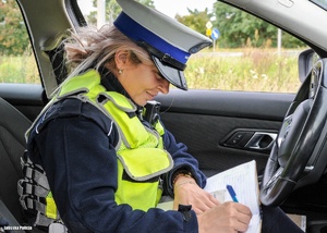 Policjantka sprawdza dokumentację kontrolowanego pojazdu.