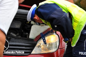 Policjant drogówki sprawdza stan techniczny pojazdu.