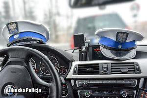 Czapki policjantów ruchu drogowego na desce rozdzielczej radiowozu.