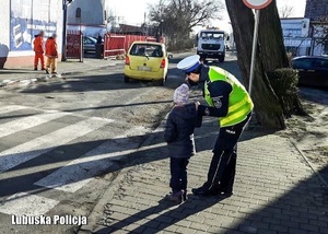 Policjantka drogówki z dzieckiem tłumaczy zasady bezpieczeństwa na drodze.
