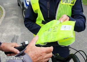 Policjantka wręcza kamizelkę odblaskową rowerzyście.