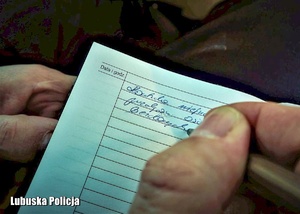 Policjant podczas dokumentowania czynności w notatniku służbowym.