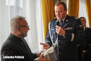 Komendant Wojewódzki Policji wręcza prezent księdzu.