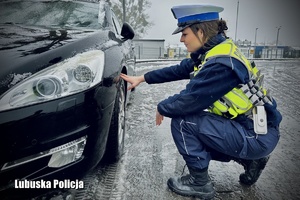 policjantka kontroluje stan ogumienia pojazdu