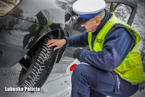 Policjant kontroluje stan opon pojazdu