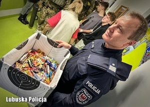 Policjant trzyma karton z cukierkami dla pacjentów