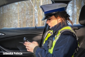 Policjantka drogówki podczas sprawdzania dokumentów kierującego.