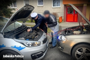 policjant pomaga odpalić auto mężczyzny poprzez kable podpięte do radiowozu