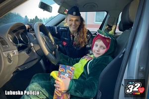 policjantka siedzi w radiowozie z dzieckiem w przebraniu krokodyla